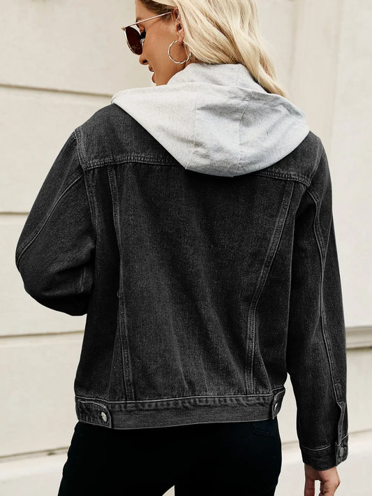 Person wearing a black denim jacket with a light gray hood against a neutral background