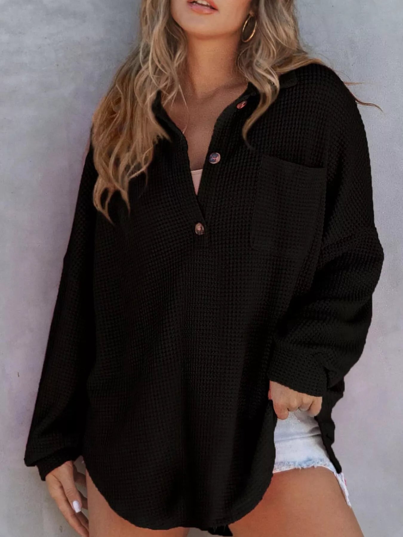 Woman wearing a black textured shirt against a neutral background