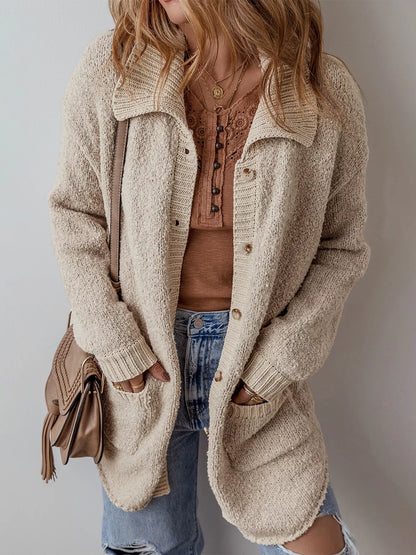 Person wearing a beige cardigan over a brown top and blue jeans, holding a brown bag.