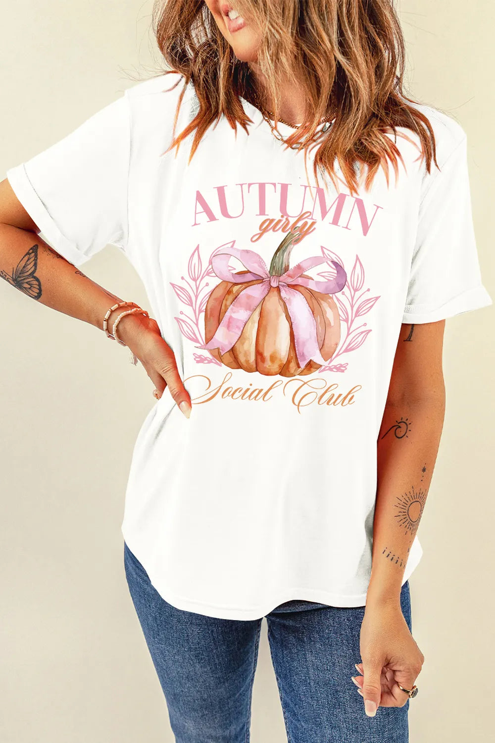 Person wearing a white t-shirt with a pumpkin graphic and text on a beige background