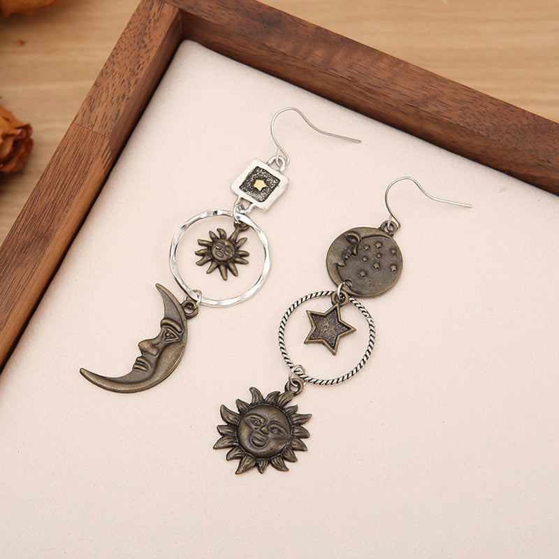 Pair of earrings with celestial designs on a wooden box.