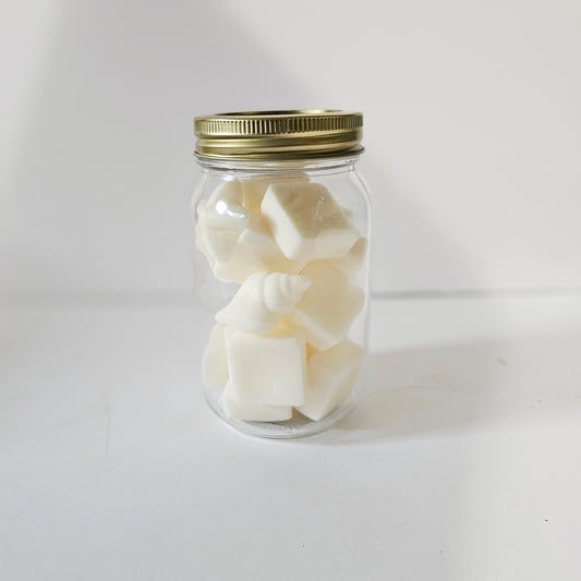 Clear glass jar with gold lid containing white cubes on a white background