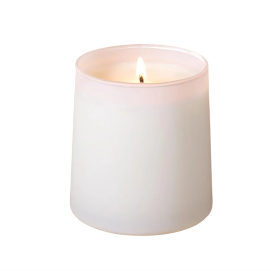White candle with a lit wick on a white background