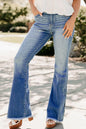 Person wearing blue flared jeans with a blurred outdoor background