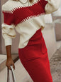 Person wearing a red and white sweater with a red skirt, holding a white handbag.