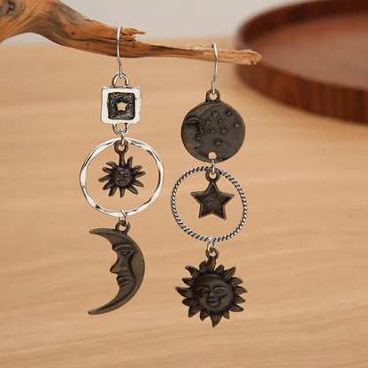 Pair of earrings with celestial designs on a wooden surface