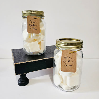Two glass jars with gold lids containing white cubes and brown labels on a white background.