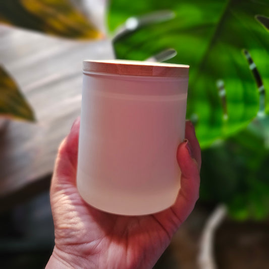 Hand holding a white cup with green plants in the background