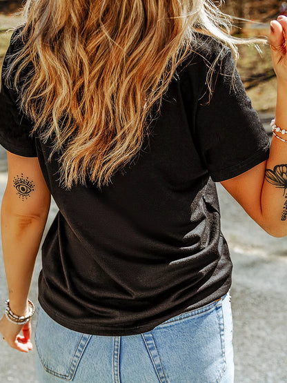 Person wearing a black t-shirt and light blue jeans with tattoos on arms.