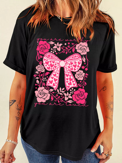 Black t-shirt with pink bow and floral design on a beige background