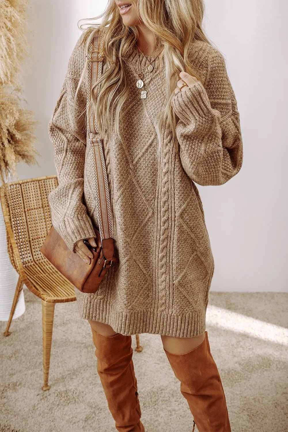 Woman wearing a beige knitted dress with brown over-the-knee boots indoors.