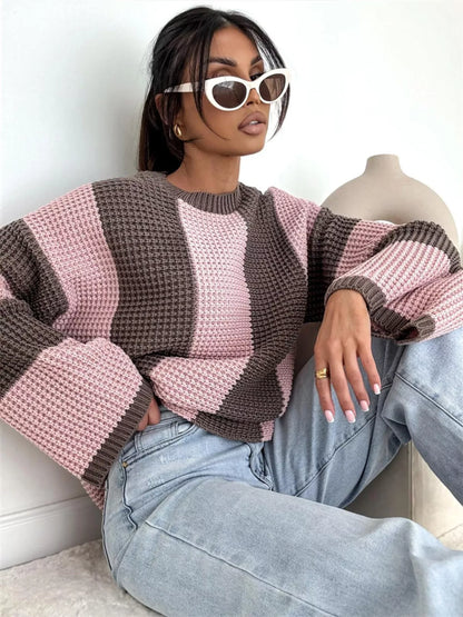 Person wearing a pink and brown striped sweater and light blue jeans, sitting on a white surface.