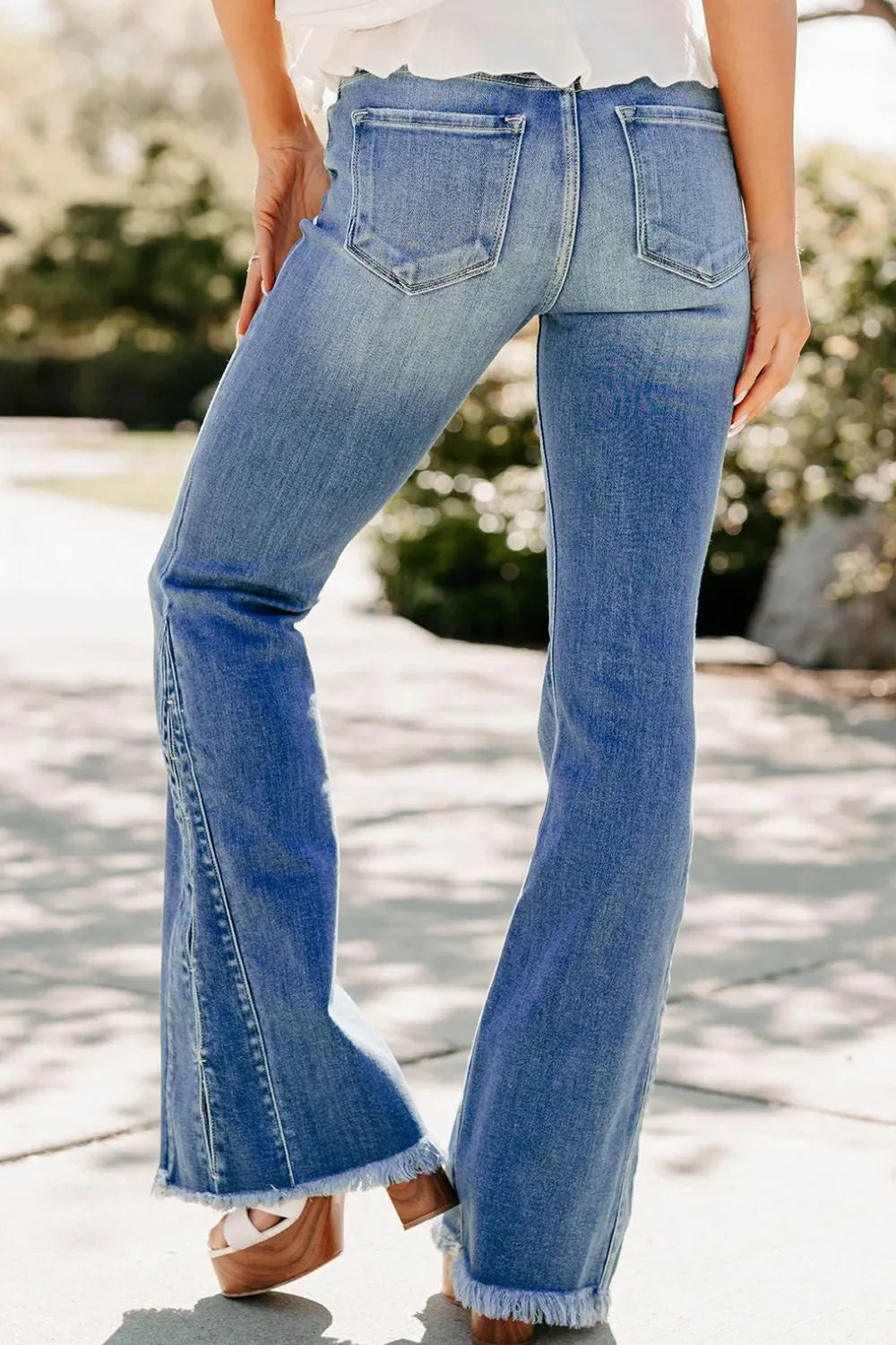 Person wearing blue flared jeans with a blurred outdoor background