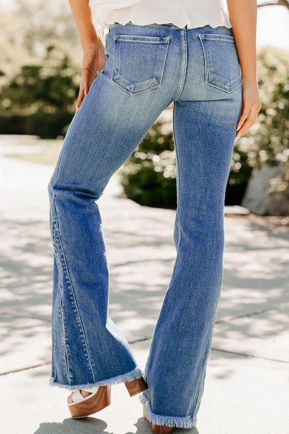 Person wearing blue flared jeans with a blurred outdoor background