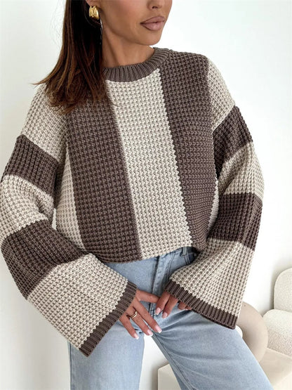Woman wearing a brown and beige striped sweater with light blue jeans on a white background